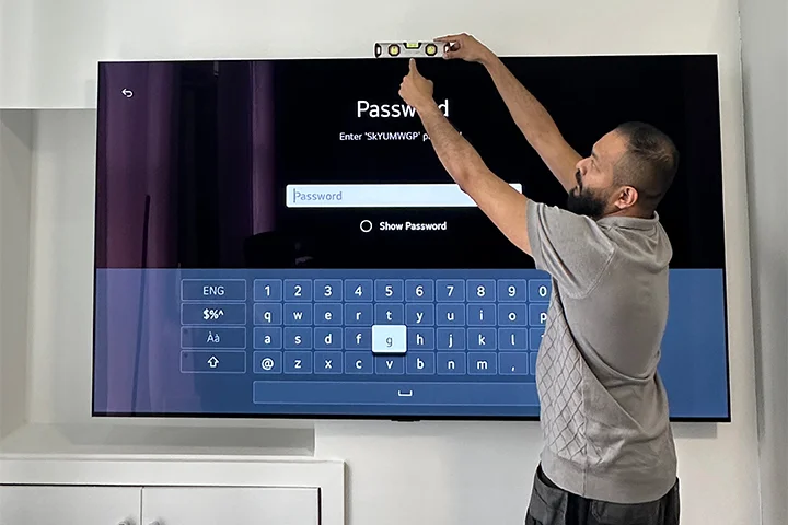 Rony from TV Mount Mate checking a wall-mounted TV is perfectly level during a professional TV installation in London