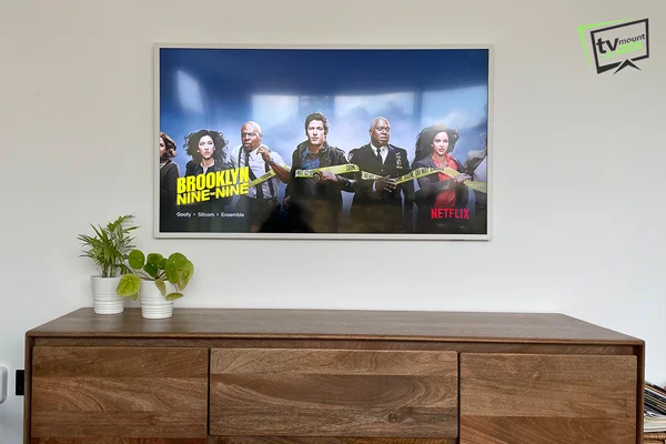 Samsung Frame TV mounted on a dot-and-dab wall above a wooden sideboard in Stockwell