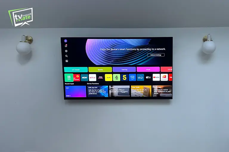 Front view of a 65-inch LG C5 OLED centred between wall lights on a plasterboard wall in East Dulwich.