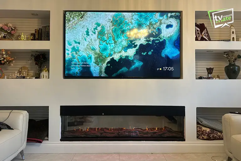 TV Mounting Above Fireplaces 4 Samsung S95F TV wall mounted above an electric fireplace on a feature wall with a soundbar and concealed cables in SE18 London.