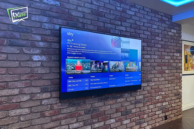 Wide view of a 65-inch Sky Glass mounted level on a brick feature wall in a Potters Bar living room.