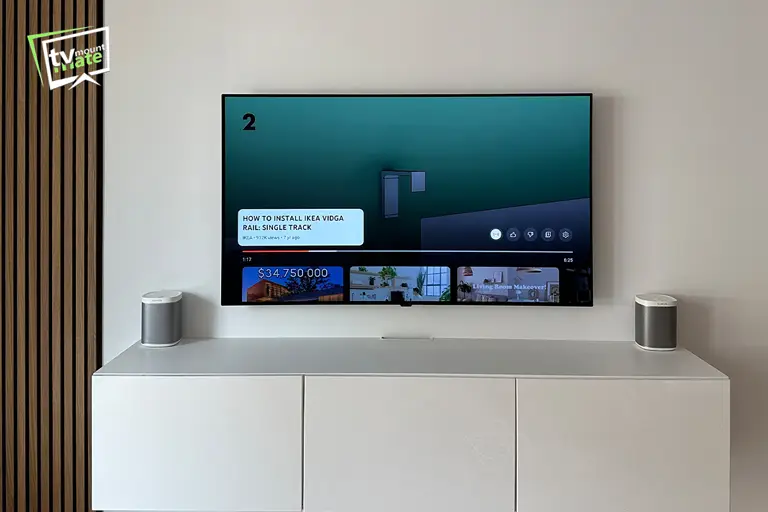 65-inch LG G5 OLED mounted above a floating white cabinet with two speakers